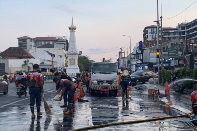 
					Petugas membersihkan luapan minyak jelantah yang terjadi di kawasan Tugu Jogja. (Foto/Kirwan)